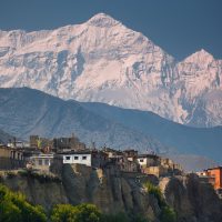 A small cliff town in front of the Himalayas in Nepal