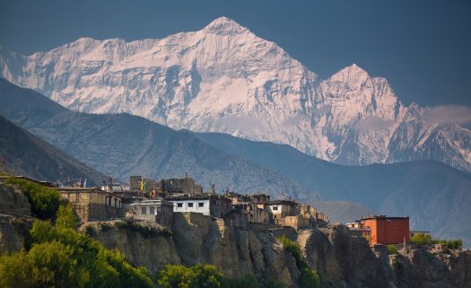 A small cliff town in front of the Himalayas in Nepal.