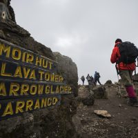 A sign on Mt. Kilimanjaro and hikers