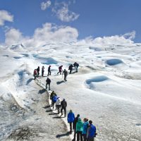 Hikers ascend a snowy path up a glacier in Patagonia.