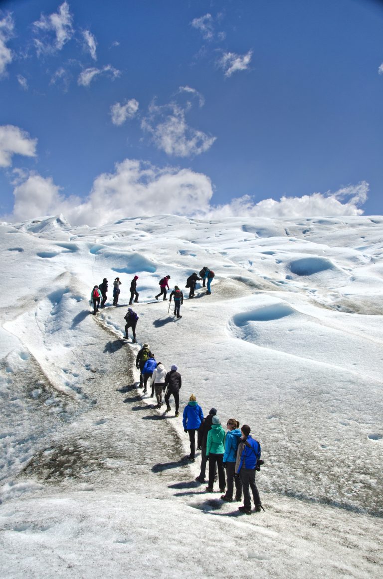 Hikers ascend a snowy path up a glacier in Patagonia.