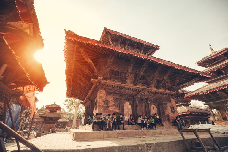 People hang out on the steps of a building at Durbar Square in Kathmandu