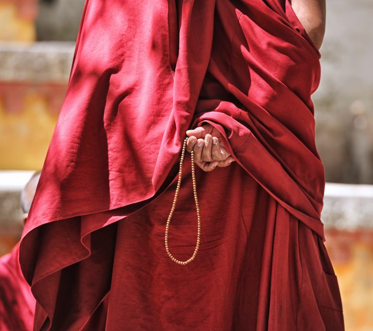Gold prayer beads in monk's hand